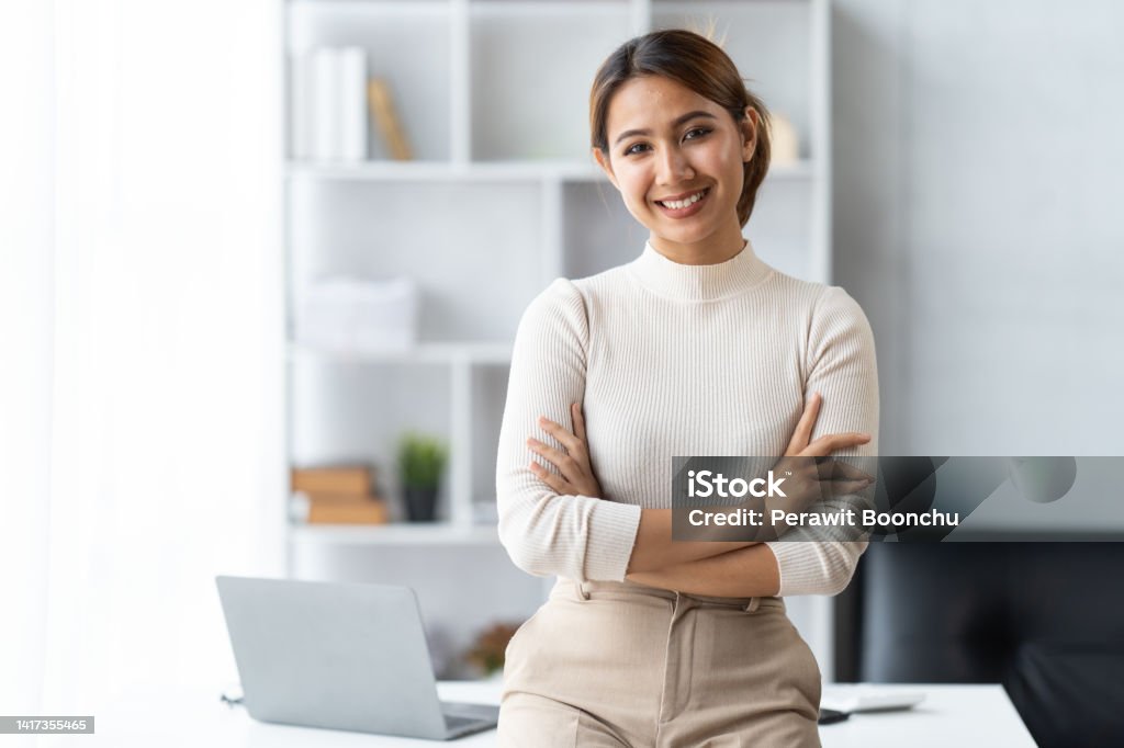 Portrait of a smiling asian businesswoman standing with arms folded and looking at camera Expertise Stock Photo