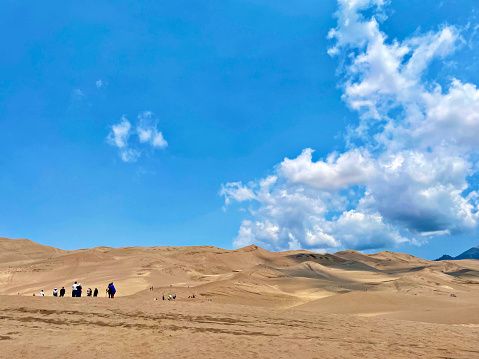 Alamosa County, Colorado, USA - July 11, 2021 - Visitors to Great Sand Dunes National Park hike on one of the many sand dunes of the namesake recreation area.