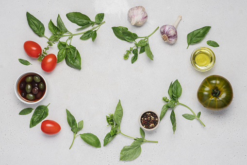 Italian food on white background. Fresh green basil, tomatoes, parmesan cheese, olives, olive oil, spices