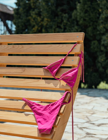 Close up photo of female swimwear drying on a long chair near pool at tourist resort.