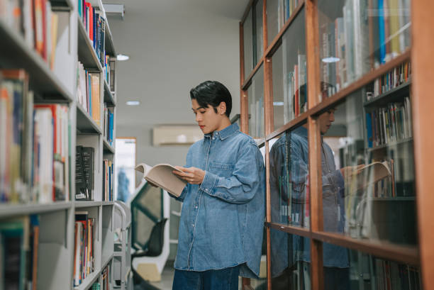 アジアのlgbtq+ゲイの成人学生が大学図書館の本棚から本を拾う - bookshelf book reference book choosing ストックフォトと画像