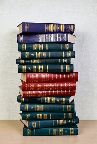 A stack of books (old) on the floor on a light blurry background. Copy space