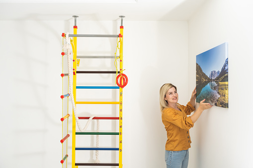 Woman hanging a photo canvas on a wall