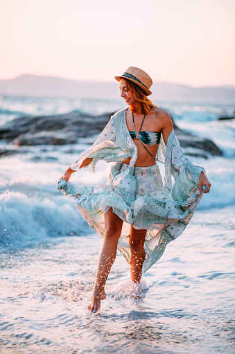 Happy Young Woman Walking in the Waves at the Beach
