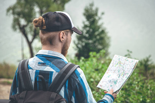Male traveler looking at the map, hiking concept. Male traveler with a backpack looking at the map, view from the back, hiking concept. irish travellers photos stock pictures, royalty-free photos & images
