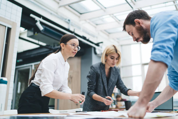 istock Group of colleagues working around table standing in office 1417379413
