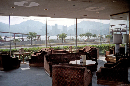 British Hong Kong, China - 1983: A vintage 1980's Fujifilm negative film scan of the downtown Hong Kong skyline through the windows of a restaurant lounge.