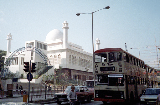 British Hong Kong, China - 1983: A vintage 1980's Fujifilm negative film scan of busy city streets in Hong Kong in front of the white Kowloon Masjid and Islamic Centre.