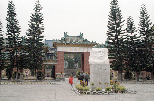 Hong Kong, China - 1983: A vintage 1980's Fujifilm negative film scan of a temple park entrance in to Kowloon Park, with Sun Yat-sen white marble bust in front of the entrance.