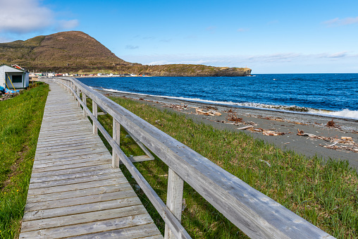 Wooden boardwalk on a sandy beach. Path leading to the beach with the sea in background.