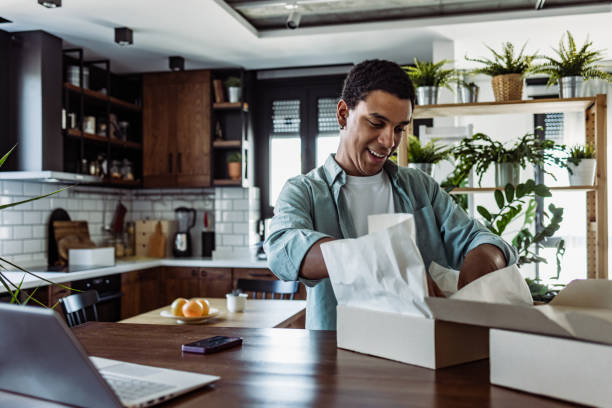 Smiling young man unboxing online purchase at home