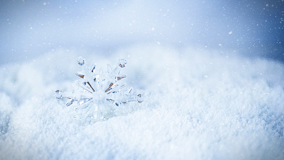 Crystal snowflake on white snow. Winter background