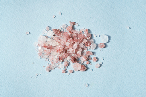 Pile of Himalayan pink salt on blue, close up.