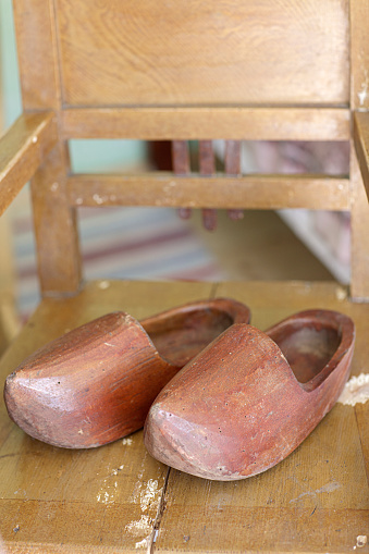 Old used traditional Dutch wooden clogs on a wooden old chair.