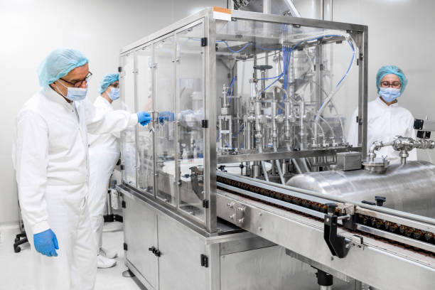 istock Three pharmaceutical colleagues seen while working on a machine that is filling the bottles during manufacturing process 1417392283