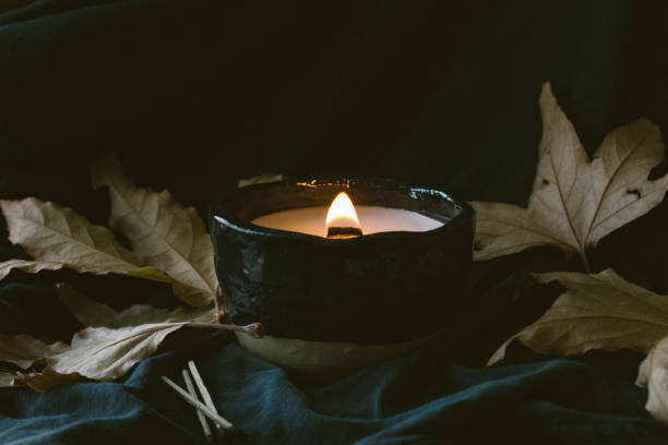 istock Lit wooden wick candle with fall leaves and dark background 1417396178