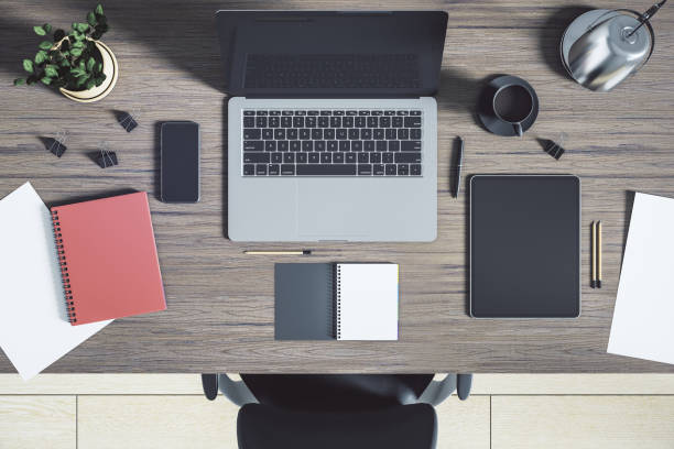 istock Top view on sunny cozy work place with modern laptop, digital tablet, flowerpot, notebooks and coffee cup on brown wooden table. 3D rendering 1417397273