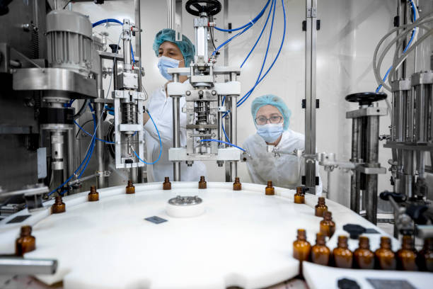 Small brown bottles seen perfectly arranged in a laboratory after production and all the proper checks during manufacturing in a pharmaceutical factory while employees are controlling the process.