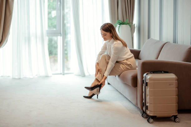 Businesswoman taking off her shoes Businesswoman on business trip in hotel room takes off her shoes Women work shoes stock pictures, royalty-free photos & images