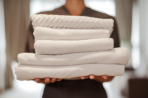 Cropped image of chambermaid with clean towels in the hotel room