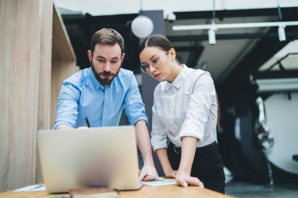 istock Adult employees discussing project while concentrating on screen and using laptop in office 1417402728