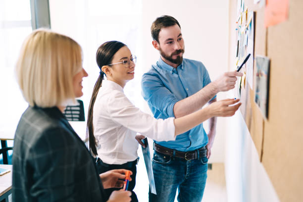 istock Creative team discussing work in office near wall with cork board 1417402779