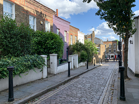 Color image depicting traditional row houses on an old fashioned narrow cobblestone street in Hampstead, London, UK. Old street. In a row.