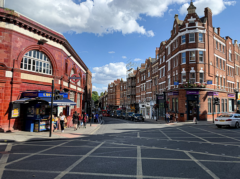 Hampstead Underground Station, London, retail shops on the background. Hampstead is an affluent residential area favoured by academics, artists and media figures. Heath street and Hampstead High street view. Victorian architecture