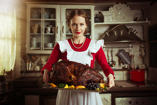 Housewife holding a large turkey in the kitchen, 50s retro style