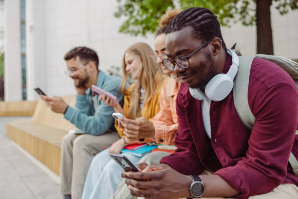 istock Group of students sitting together and using their smart phones 1417404933