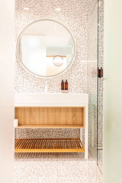 istock White sink on counter with a round mirror hanging above it. Bathroom interior. Modern bathroom interior with stylish mirror and vessel sink. 1417413306