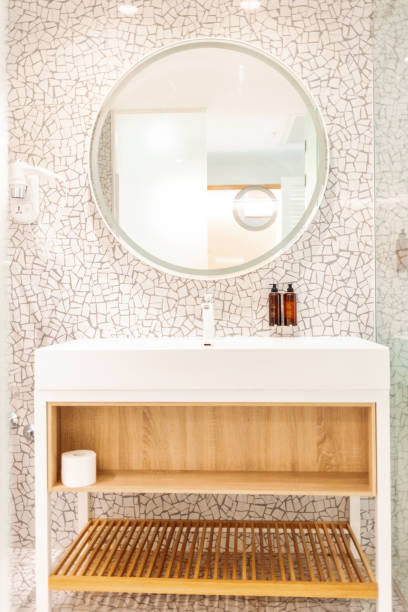 istock White sink on counter with a round mirror hanging above it. Bathroom interior. Modern bathroom interior with stylish mirror and vessel sink. 1417413316