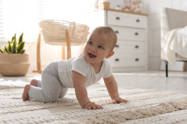 Cute baby crawling on floor at home stock photo