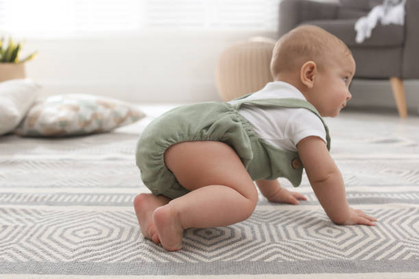istock Cute baby crawling on floor at home 1417415212