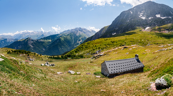 Panoramic view of beautiful winter wonderland mountain scenery in the Alps with traditional mountain chalets on a cold sunny day with blue sky and clouds