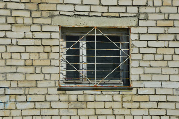 a window with a rusty metal grille, a white brick wall. background for the design.