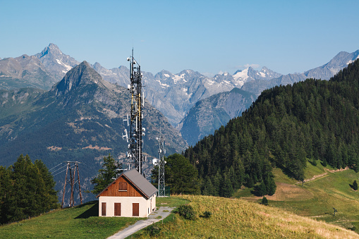 Small communications antenna technology in middle of Alps mountains during a sunny summer day. Taken near Ornon small village in Oisans massif, in Isere, Auvergne-Rhone-Alpes region in France.