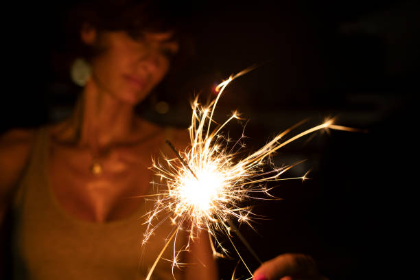 istock Woman, blurred face, holding a burning sparkler in the dark. Copy space. 1417418193