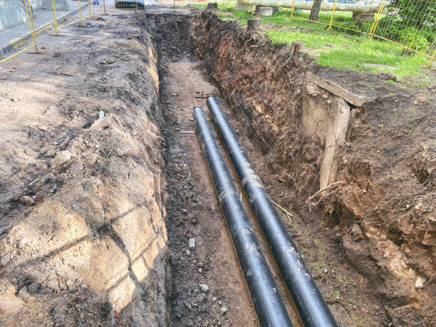 tendido de comunicaciones subterráneas para edificios residenciales. las tuberías de plomería negras hechas de material duradero y confiable están enterradas profundamente en una zanja de tierra - boca de alcantarilla fotografías e imágenes de stock