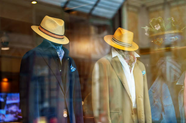 Men mannequins advertise summer clothes behind glass.