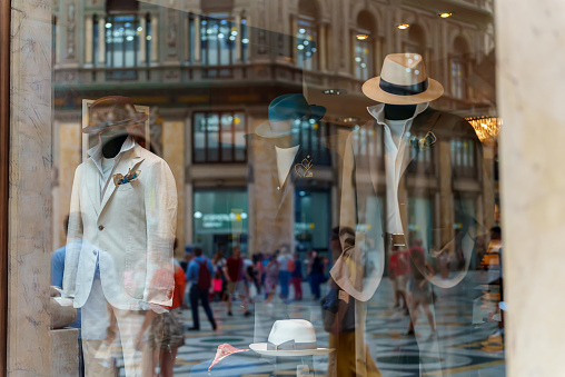 Men mannequins advertise summer clothes behind glass.