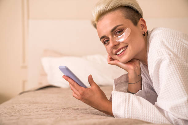 istock Blonde woman with under eye face mask smiling warmly while looking at the camera 1417421145