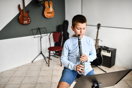 Focused Male Child Ready To Read New Piece On Clarinet From Sheet Music