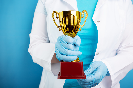 award cup in doctor's hands on blue background