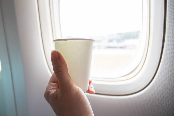 istock airplane drinks, a hand with a cup of coffee inside the plane at the window 1417422423