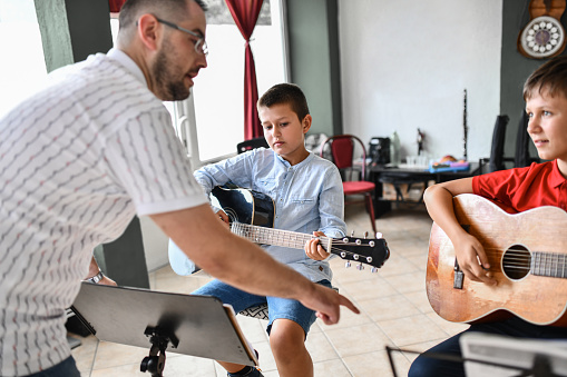 Teacher Getting Close To Guitar Students To Point Out Mistakes