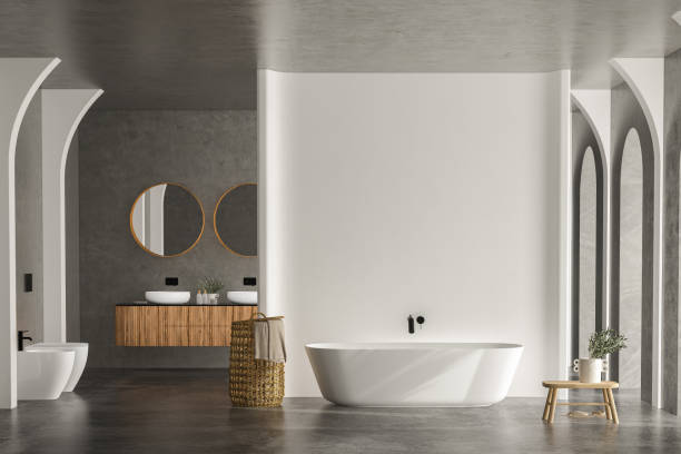 istock Bright bathroom interior with concrete floor and wall, white bathtub and two sinks 1417432351
