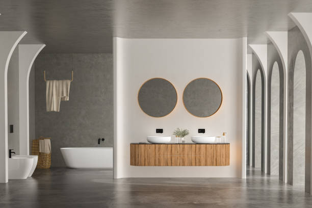 istock Bright bathroom interior with concrete floor and wall, white bathtub and two sinks 1417433798