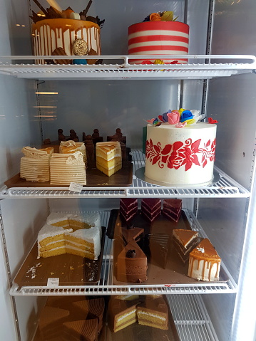 Close-Up of different types of fresh cakes in display cabinet for sale at store.