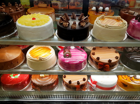 Close-Up of different types of fresh cakes in display cabinet for sale at store.